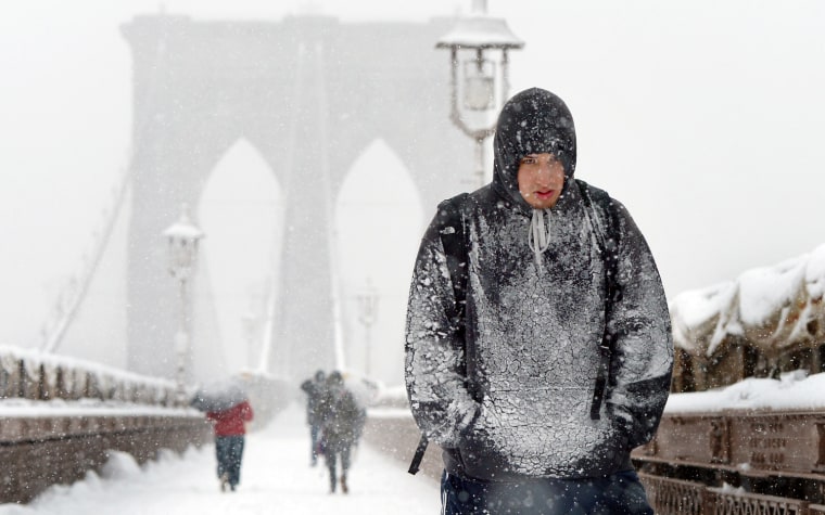 A man covered in snow walks across the Brooklyn Bridge during a snow storm in New York, on March 8.