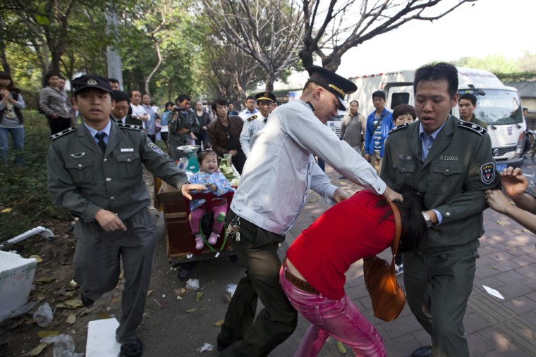 Law enforcement officers tackle fruit seller Li Shengyan in Guangzhou, China, in an incident that turned into a public relations nightmare for the authorities.