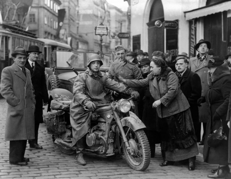 Passersby offer flowers to a German soldier in a street of Vienna to welcome the German Nazi troops on March 15, 1938 after the Anschluss, the invasion of Austria by the troops of the German Wehrmacht.