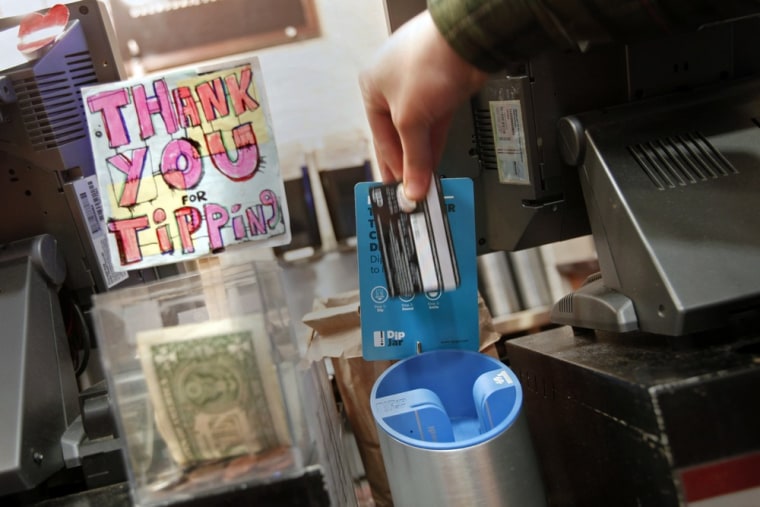 A man demonstrates the use of a DipJar, an electronic version of the tip jar found in coffee shops, on the counter of an Oren's Daily Roast in New Yor...