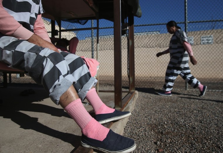 An immigrant inmate exercises while another sits on his bunk at the Maricopa County Tent City jail on March 11, 2013. Striped uniforms and pink undergarments are standard issue at the facility.