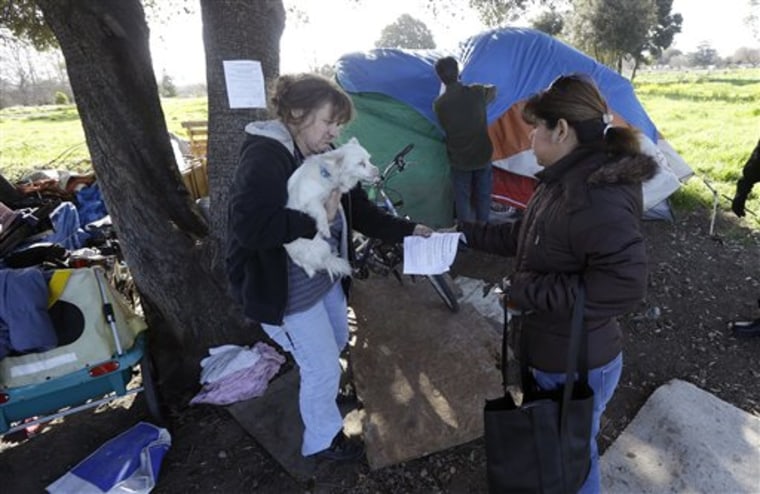 Wendy Carle, left, holds her neighbor's dog, Hero, as she is handed an eviction notice by San Jose city worker Rita Tabaldo on March 5 at a tent city in San Jose, Calif.