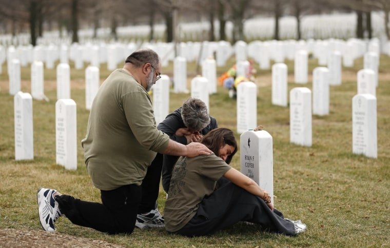 Tony Coyer puts his hand on the shoulder of his daughter Lesleigh as his wife Mary weeps while visiting the grave of his son.