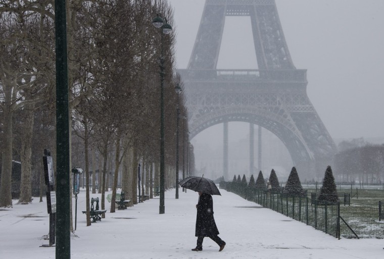 A pedestrian braves heavy snowfall on the snow-covered Champs de Mars near the Eiffel Tower in Paris on March 12, 2013.