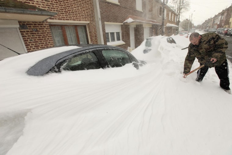 A man shovels snow off his car in Cambrai, northern France, on March 12, 2013.