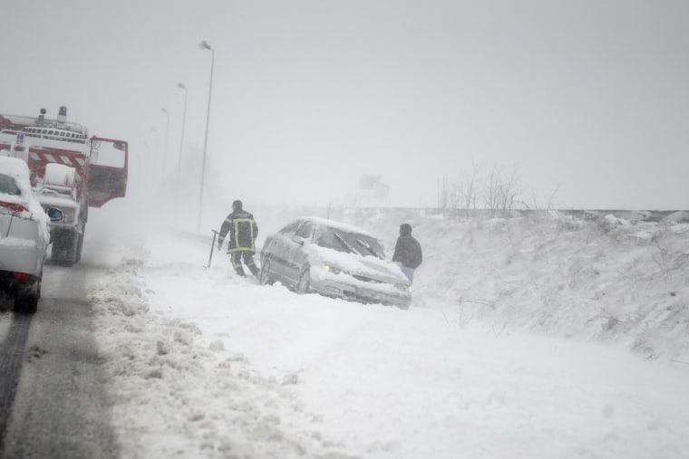 Firefighters rescue a driver who slid from a roadside during a heavy snowstorm in Caen, northwestern France, on March 12, 2013.