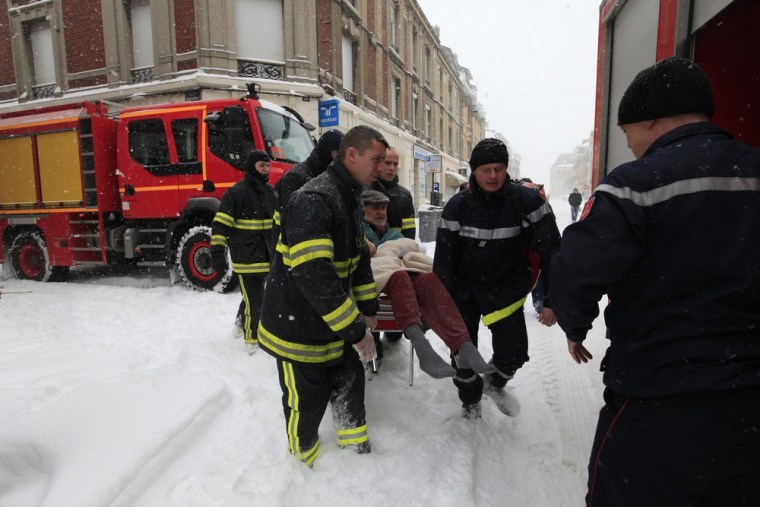 Firefighters evacuate a man in Cambrai, northern France, on March 12, 2013 as winter weather with snow and freezing temperatures returns to the region.