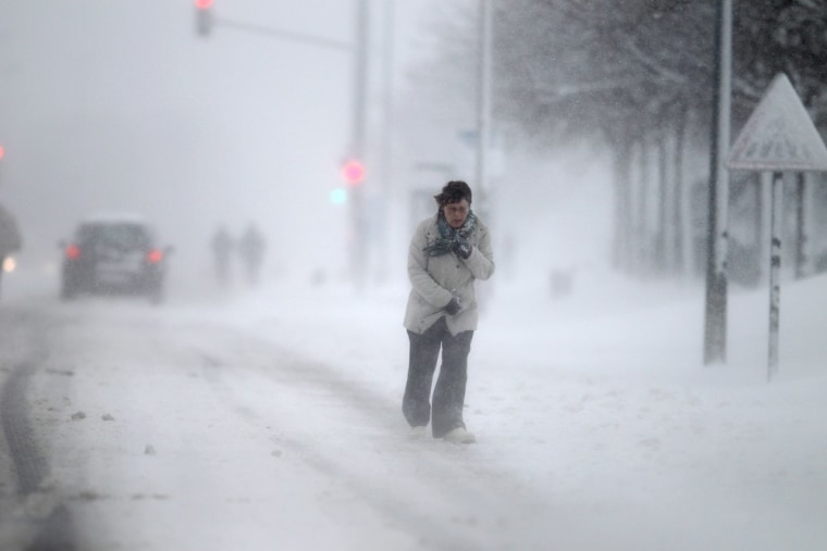 A woman walks on a snowy road in Caen, northwestern France, during a heavy snowstorm on March 12, 2013. Overnight Monday nearly 500 cars were blocked near Cherbourg, where snowdrifts piled up almost two feet as winds reached more than 60 miles an hour.