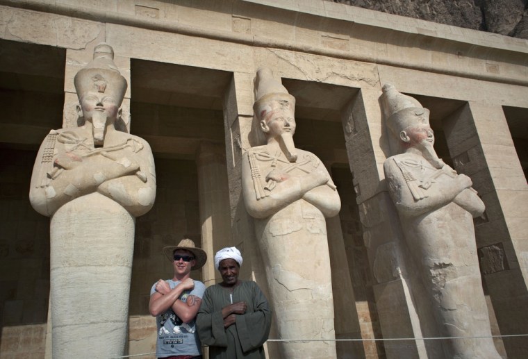 A foreign tourist takes a souvenir picture with an Egyptian guard during a visit to the Hatshepsut Temple, in Luxor, Egypt on Feb. 27, 2013.