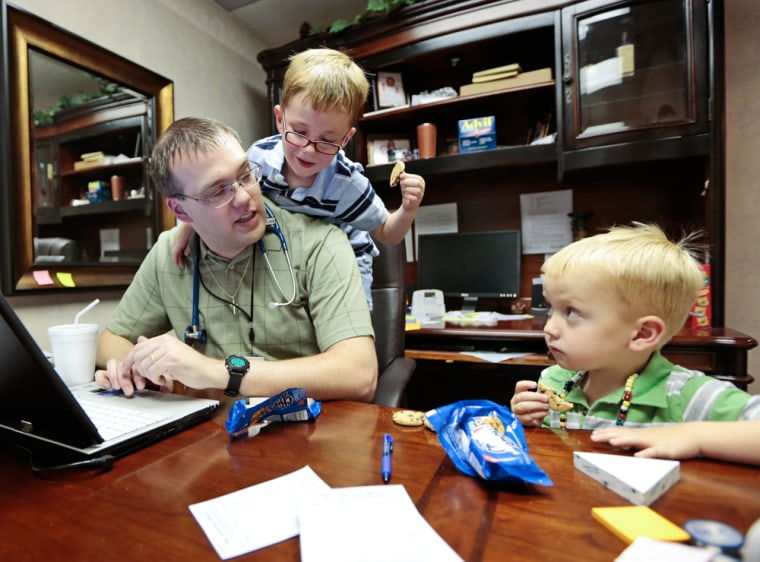 Dustin Baylor, seen here in 2012 with sons Paxton, left, and Garrison, has struggled to balance his responsibilities as a doctor and a dad. A new Pew study finds that nearly as many dads as moms find it hard to juggle work and family responsibilities.