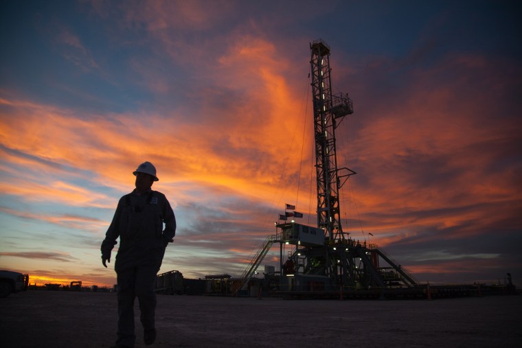 A worker walks from the 161-foot-tall rig to retrieve a tool from a nearby shed, Sunday, March 3, 2013, in West Texas. When this picture was made o...