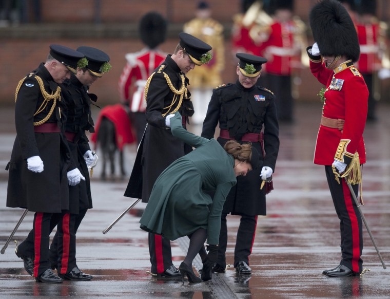 Britain's Prince William supports his wife, Catherine, Duchess of Cambridge, as she pulls her heel from a grate during a St. Patrick's Day visit to Mons Barracks in Aldershot, southern England, on March 17.