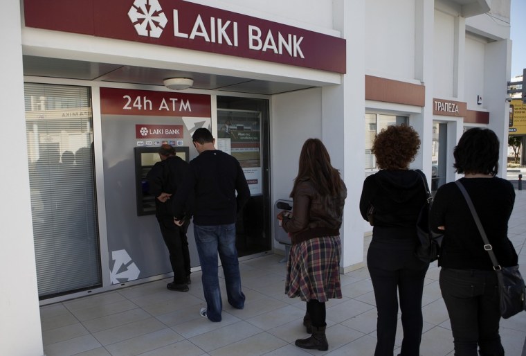 People line up to use an ATM machine outside of Laiki Bank branch in Larnaca, Cyprus, on Saturday. Many rushed to cooperative banks which are open Saturdays in Cyprus after learning that the terms of a bailout deal that the cash-strapped country hammered out with international lenders includes a one-time levy on bank deposits.