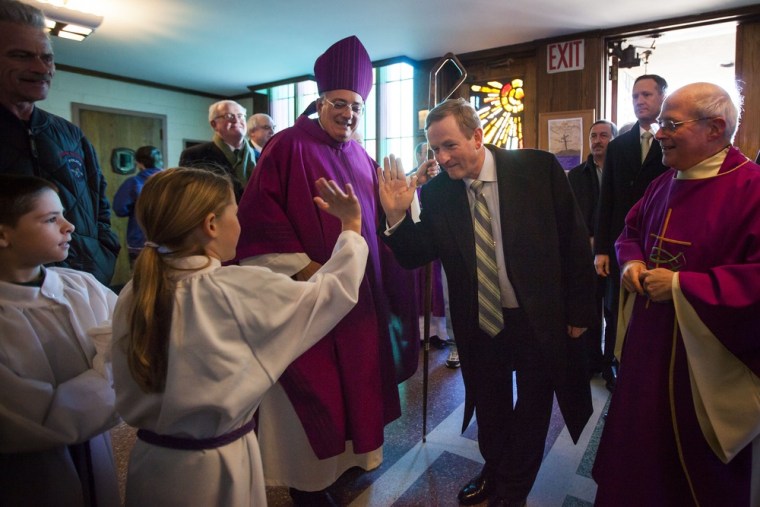 NEW YORK, NY - MARCH 17: Irish Prime Minister Enda Kenny (C) flanked by Rev. Nicholas DiMarzio (L), Bishop of Brooklyn, and Monsignor Michael J. Curran (right), pastor of St. Thomas More Church, hi-fives an alter girl as he arrives at St Thomas More Church for Saint Patrick's Day Mass on March 17, 2013 in Breezy Point.
