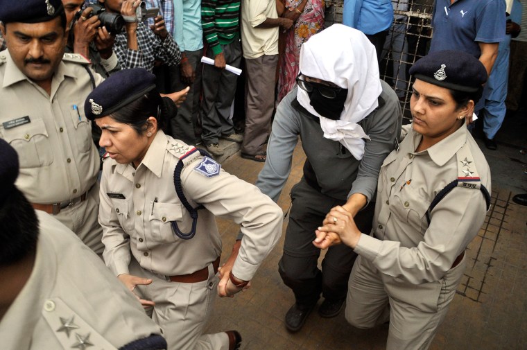 A Swiss woman, center, who, according to police, was gang-raped by a group of eight men while touring by bicycle with her husband, is escorted by policewomen for a medical examination at a hospital in Gwalior, in the central Indian state of Madhya Pradesh, Saturday, March 16, 2013. Thirteen men were detained and questioned in connection with the attack, which occurred Friday night as the couple camped out in a forest after bicycling from the temple town of Orchha, local police officer R.K. Gurjar said. The men beat the couple and gang-raped the woman, he said.