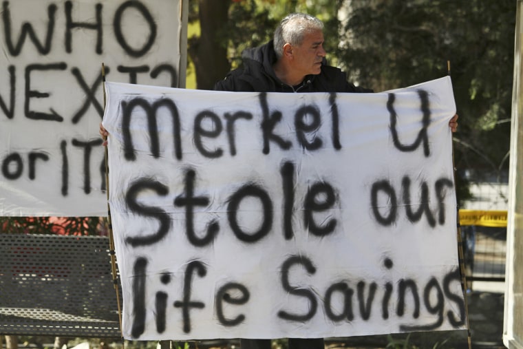 A man holds a banner against German Chancellor Angela Merkel's call for Cyprus to follow economic reforms.