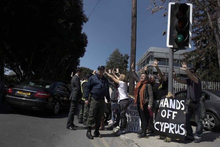 Demonstrators raise their arms in protest as Cypriot President Nicos Anastasiades's convoy drives to the parliament in Nicosia, Monday.