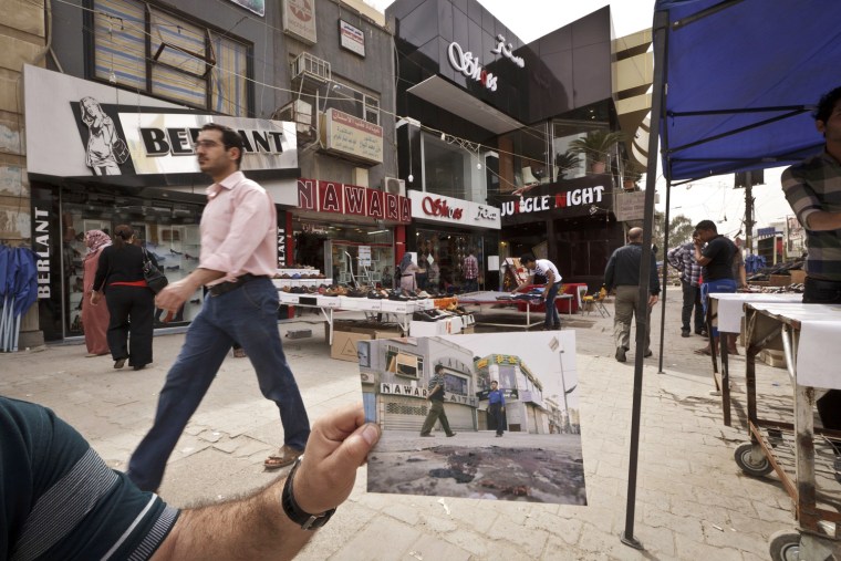 In this Saturday, March 16, 2013 photo, shoppers walk in Baghdad's busy shopping district of Karrada, at the same site of an Associated Press photo taken by Hadi Mizban on Monday, Sept. 29, 2008 after a bombing that killed 22 people. Bloody attacks launched by terrorists who thrived in the post-invasion chaos are painfully still frequent, albeit less so than a few years back, and sectarian and ethnic rivalries are again tearing at the fabric of national unity.