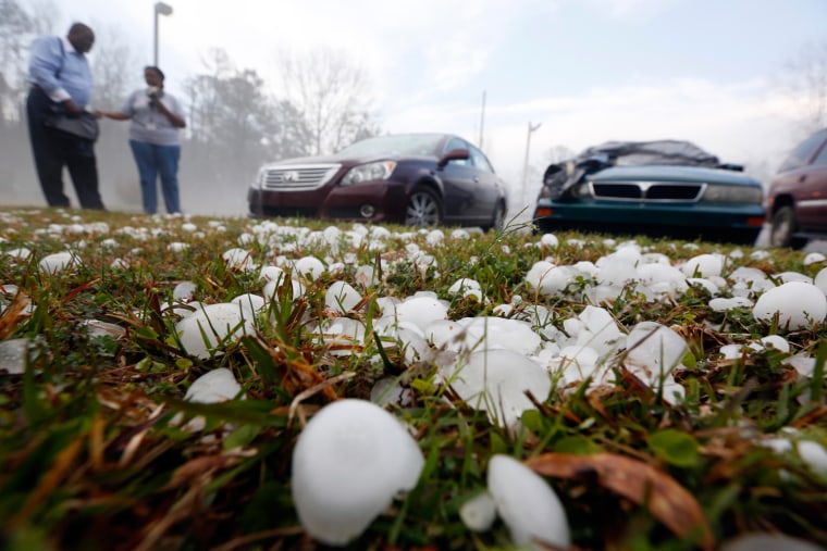 Golfball sized hail litter the ground by Andrew Stamps and his wife Valorie as they prepare to cover their shattered rear window of her 2009 Toyota Avalon in Pearl, Miss., March 18, following a hailstorm that hit communities throughout central Mississippi.