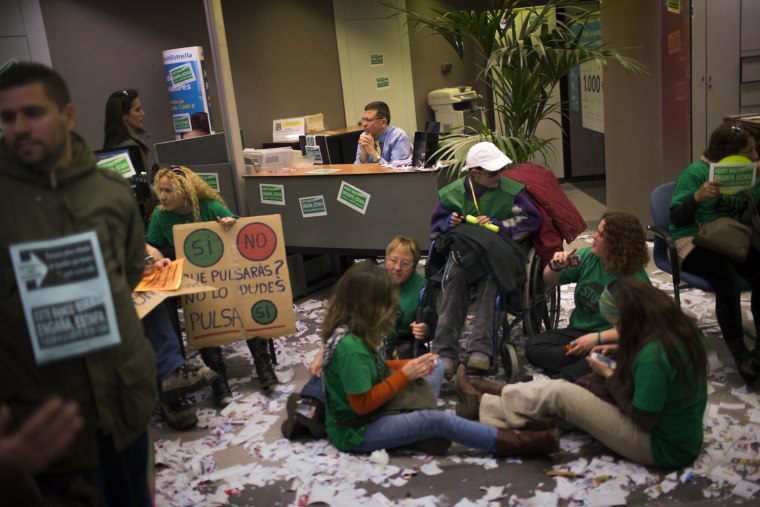 Members of Mortgage Victims' Platform (PAH), occupy a bank branch during a protest to support neighbors who are facing evictions processes in Barcelona, Spain, on March 19. With 26 percent unemployment, Spain is struggling to emerge from its second recession in just over three years. Spain's borrowing costs have dropped in recent months with investors less wary since European authorities announced the country would be helped, if needed, to handle its debt.