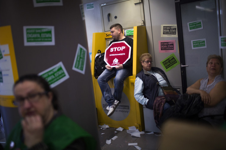 Members of Mortgage Victims' Platform (PAH), occupy a bank branch during a protest to support neighbors who are facing evictions processes in Barcelona, Spain, Tuesday March 19, 2013. With 26 percent unemployment, Spain is struggling to emerge from its second recession in just over three years.
