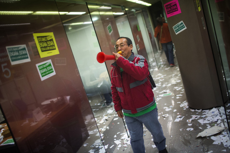 A member of Mortgage Victims' Platform (PAH) blows an air horn as he occupies, with others, a bank branch during a protest to support neighbors who are facing the eviction process in Barcelona, Spain, on March 19.