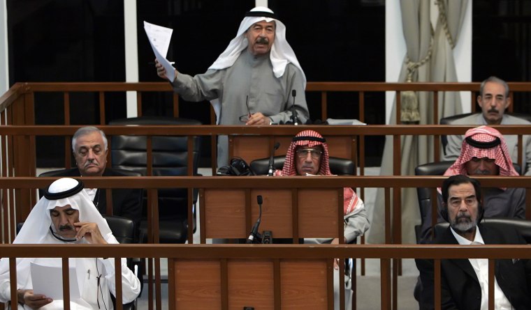 Ali Hassan al-Majid addresses the court during his trial in Baghdad's heavily fortified Green Zone on Oct. 18, 2006. Oct. 18, 2006. The co-defendents in the first row (L to R) are Farhan Salih and Saddam Hussein. In the second row (L to R) are Sabir Aba al-Aziz, Hussein Rashid Muhammad, Sultan Hashim Ahmad al-Tai and in the third row is Taher al-Ani (R).