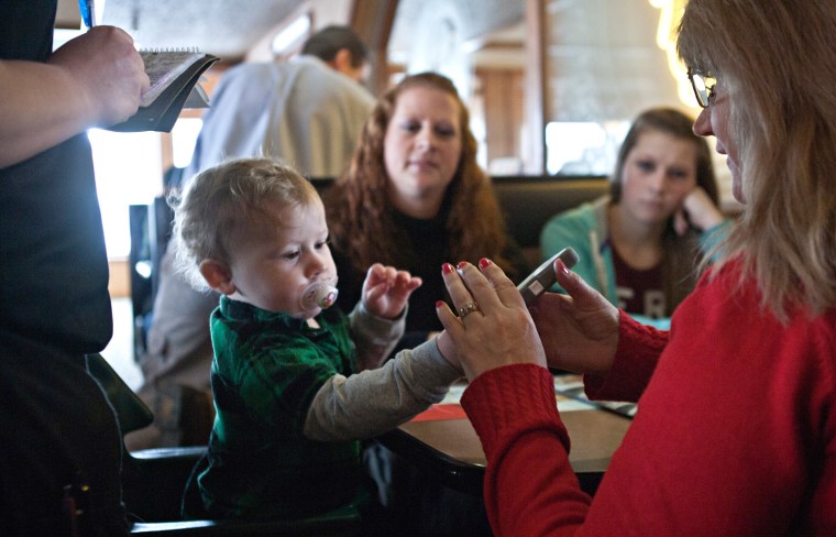 Shelly Sachwitz hands  an iPhone with a game on the screen to  her one-year-old grandson Lucas.
