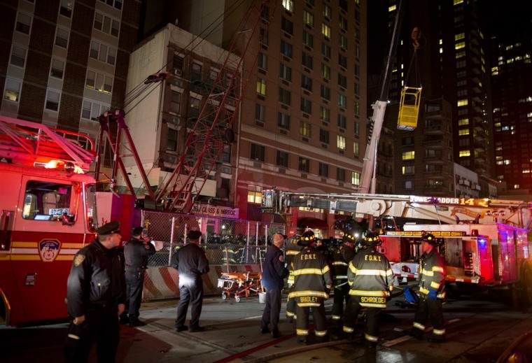 A construction transport bucket, right, is moved into place at the scene where a worker was trapped underground at an MTA subway construction project in New York on March 19.