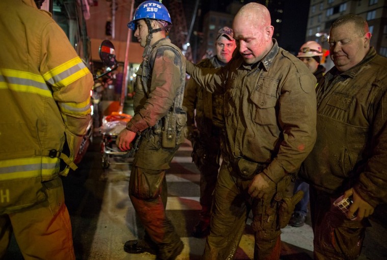 Officers from the New York City police Emergency Services Unit, covered in mud and dirt, walk to a waiting bus to warm up after rescuing a construction worker trapped underground at an MTA subway construction project in New York early on March 20. The worker, trapped for several hours, was lifted from underground with the assistance of the New York police and fire departments.