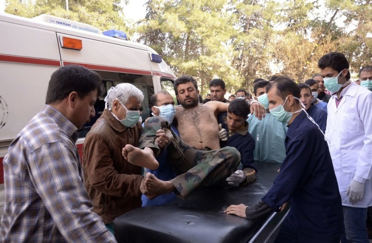 Residents and medics transport an injured Syrian army soldier after an alleged chemical weapon attack near Aleppo Tuesday.