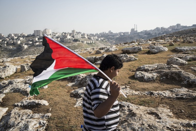 A kid holds a Palestinian flag as Palestinians erect protest tents in a camp on March 20, in the E1 area next to Ma'ale Adumim. The action took place at the same time as U.S. President Barack Obama arrived to Ben Gurion airport near Tel Aviv.