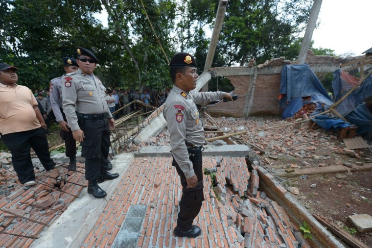 Police watch while an excavator demolishes the church building on March 21, 2013.