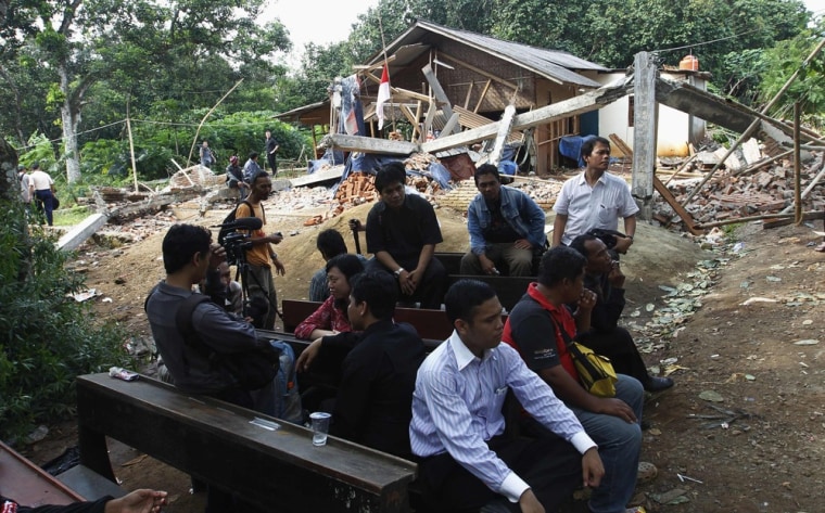 Members of the congregation of Batak Christian Protestant Church sit near the ruins of their church after an excavator demolished it on March 21, 2013.