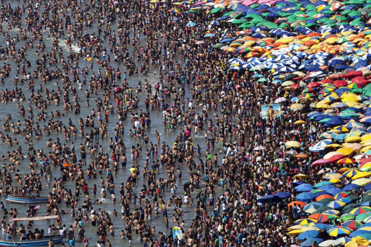Beach goers wade on the shoreline of Agua Dulce beach, in Lima, Peru during summertime in the southern hemisphere.