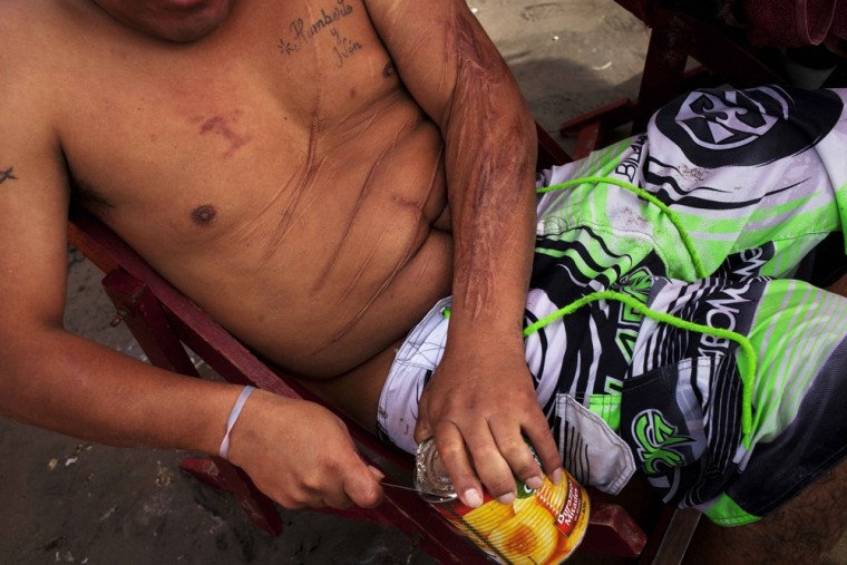 A man opens a can of peaches on Agua Dulce beach in Lima, Peru.