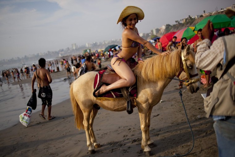 Adela Cabrera, 19, poses for a picture on a horse at Agua Dulce beach in Lima, Peru. For five Peruvian soles or about two U.S. dollars beach goers can pose for a photo to record their day at the beach.