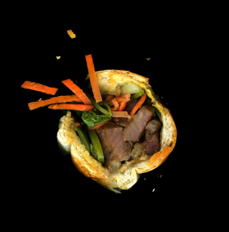 An example of the Vietnamese banh mi: pork chop, pickled carrots, cucumber, cilantro, and mayo on a toasted baguette.