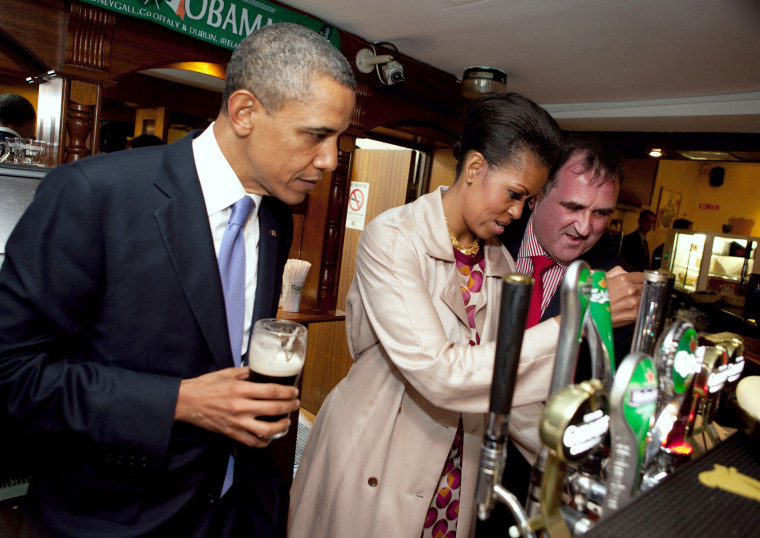 President Barack Obama watches as First Lady Michelle Obama draws a pint at Ollie Hayes Pub in Moneygall, Ireland.