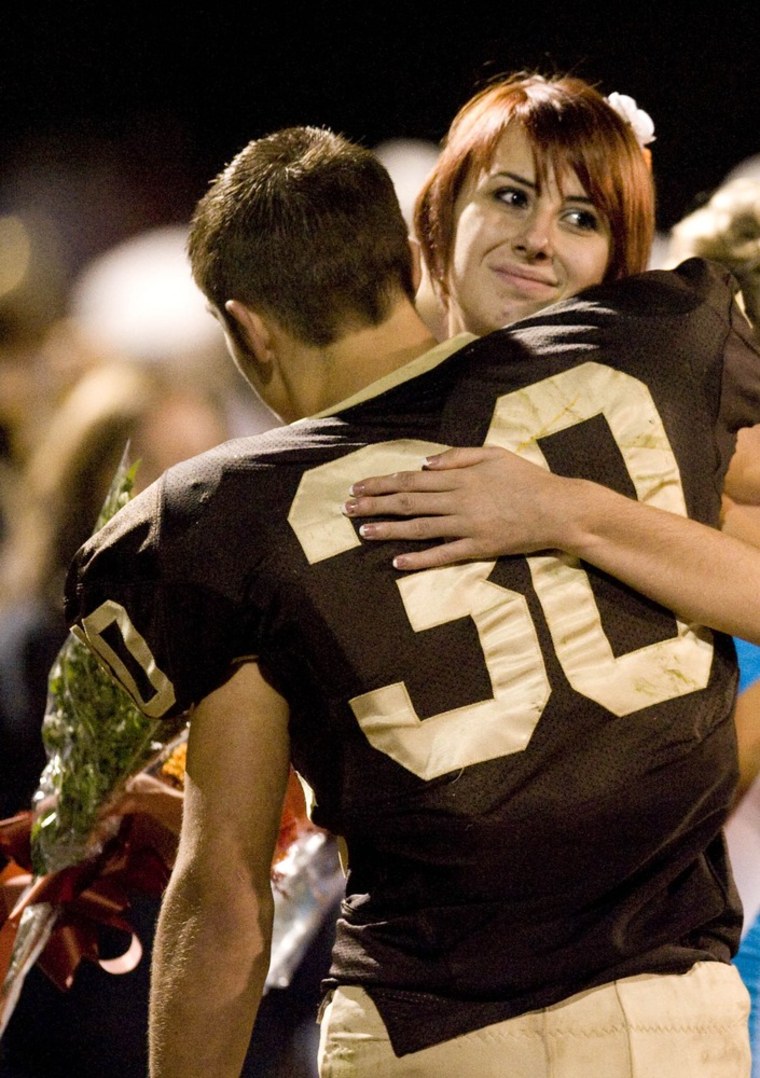 Sophomore homecoming representatives Whitney Kropp and Josh Awrey give each other a hug during the homecoming ceremony on the Ogemaw Heights High School football field on Friday.