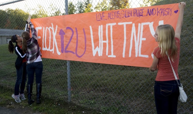 Kristy Erway, Hannah Gebnard, and Paige Sharp of Cadillac High School hang a banner in support of Whitney Kropps in West Branch, Mich., on Friday.