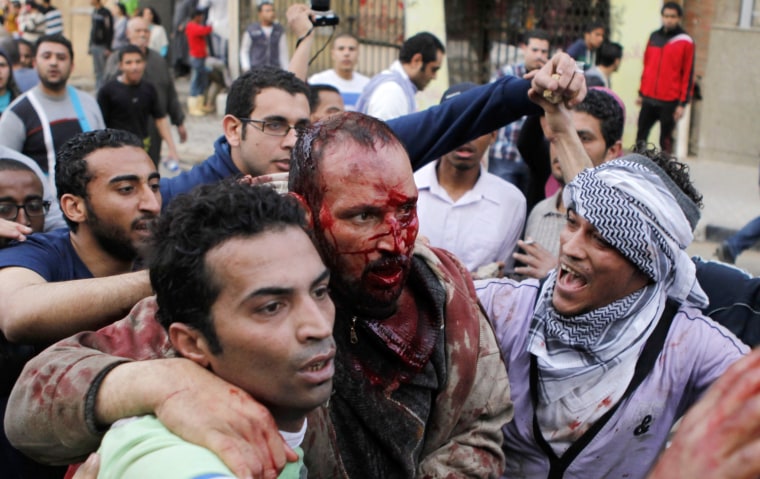 Anti-Mursi protesters carry a Muslim Brotherhood member after hitting him during clashes near the Muslim Brotherhood's national headquarters in Cairo on March 22, 2013.
