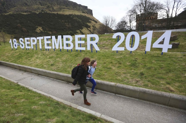 A teacher and schoolgirl run in front of a sign indicating the date of Scotland's independence referendum outside the Scottish Parliament in Edinburgh on Thursday.