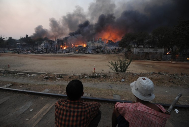 Residents sit on a railway track watching buildings burn around a mosque in riot-hit Meikhtila on March 21, 2013.