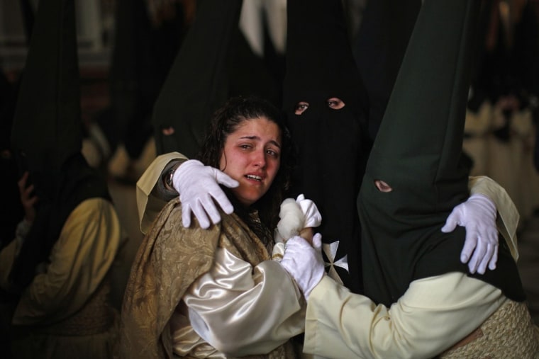 A crying woman is comforted by fellow penitents inside a church where they took shelter from the rain during the