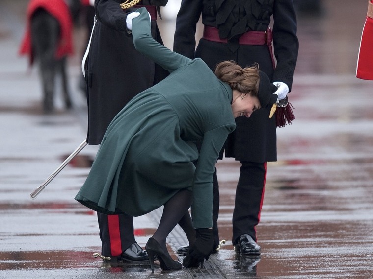 BBritain's Prince William (L) supports his wife Catherine, Duchess of Cambridge as she pulls her heel from a grate during a visit on St Patrick's Day to Mons Barracks in Aldershot, southern England.
