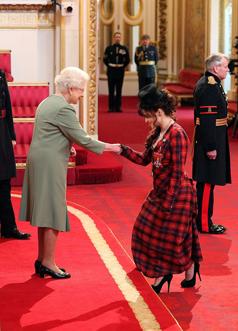 Queen Elizabeth II presents Helena Bonham Carter with a medal at Buckingham Palace on February 22, 2012.