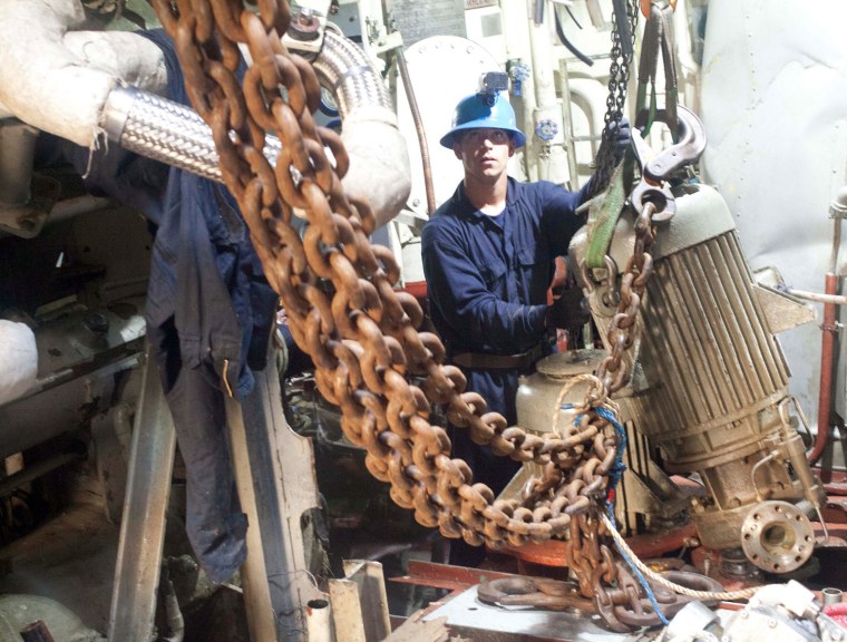 March 21: Navy Diver 2nd Class Matthew Costa, assigned to Mobile Diving and Salvage Unit (MDSU) 1, guides a piece of equipment being lifted from the engine room compartment.