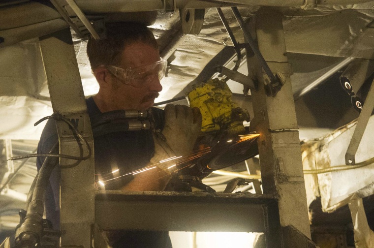 March 11: Hospital Corpsman 1st Class Brandon Berry, assigned to Mobile Diving and Salvage Unit (MDSU) 1, grinds through steel in the engine room compartment in preparation for removal of machinery.
