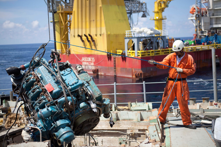 March 13: A civilian crew member of the M/V Jascon 25 guides an engine salvaged from the Guardian.